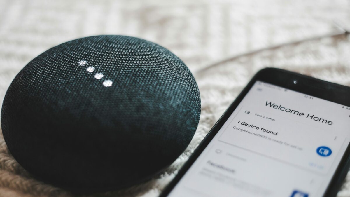 turned-on charcoal Google Home Mini and smartphone